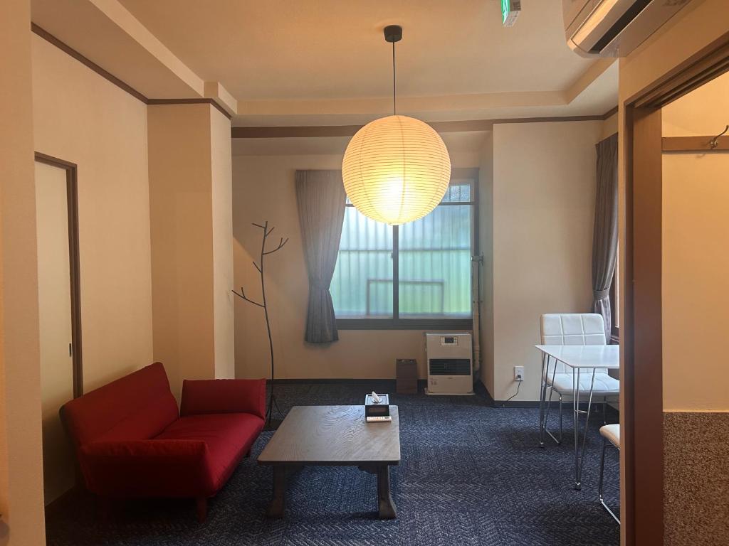 Una sala de estar con un sofá rojo y una mesa. en 山荘 ひとやね -Sansou Hitoyane-, en Sapporo
