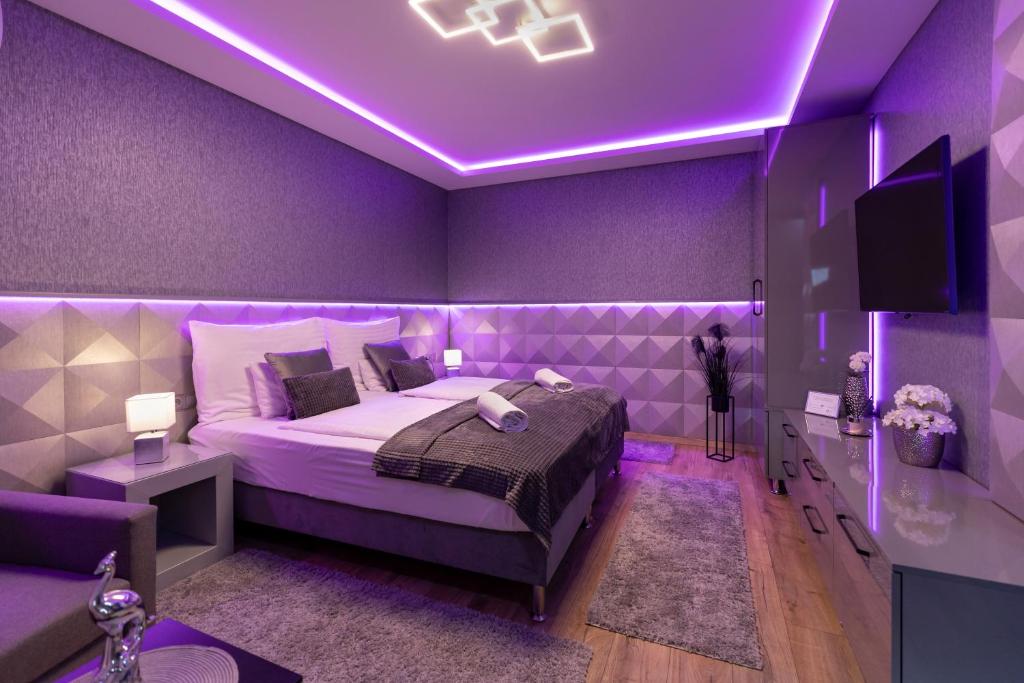 a purple bedroom with a bed and a purple lighting at Royal Apartments Gold-Silver Kecskemet in Kecskemét