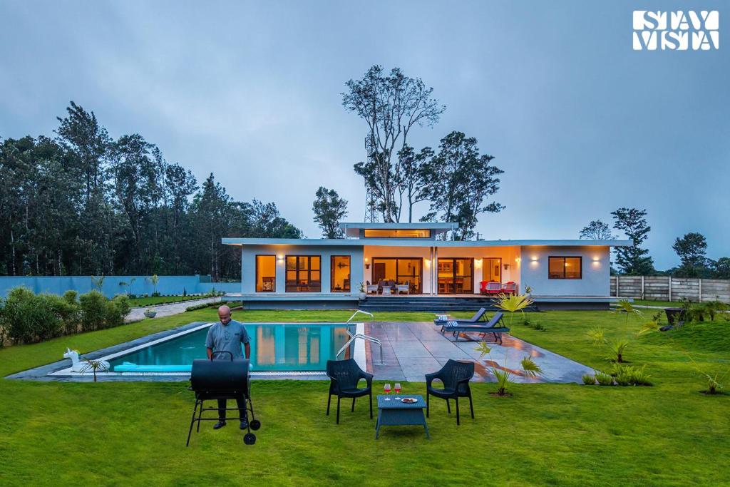 un hombre parado frente a una casa con piscina en Stayvista at Serenova with big pvt pool and lawn - Your Luxury escape awaits !, en Madikeri