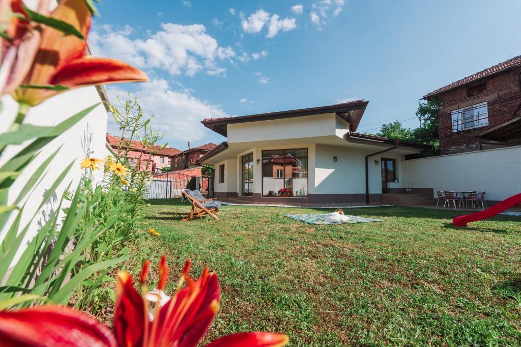 a yard with red flowers and a house at Pavlina Guest House in Tsŭrvishte
