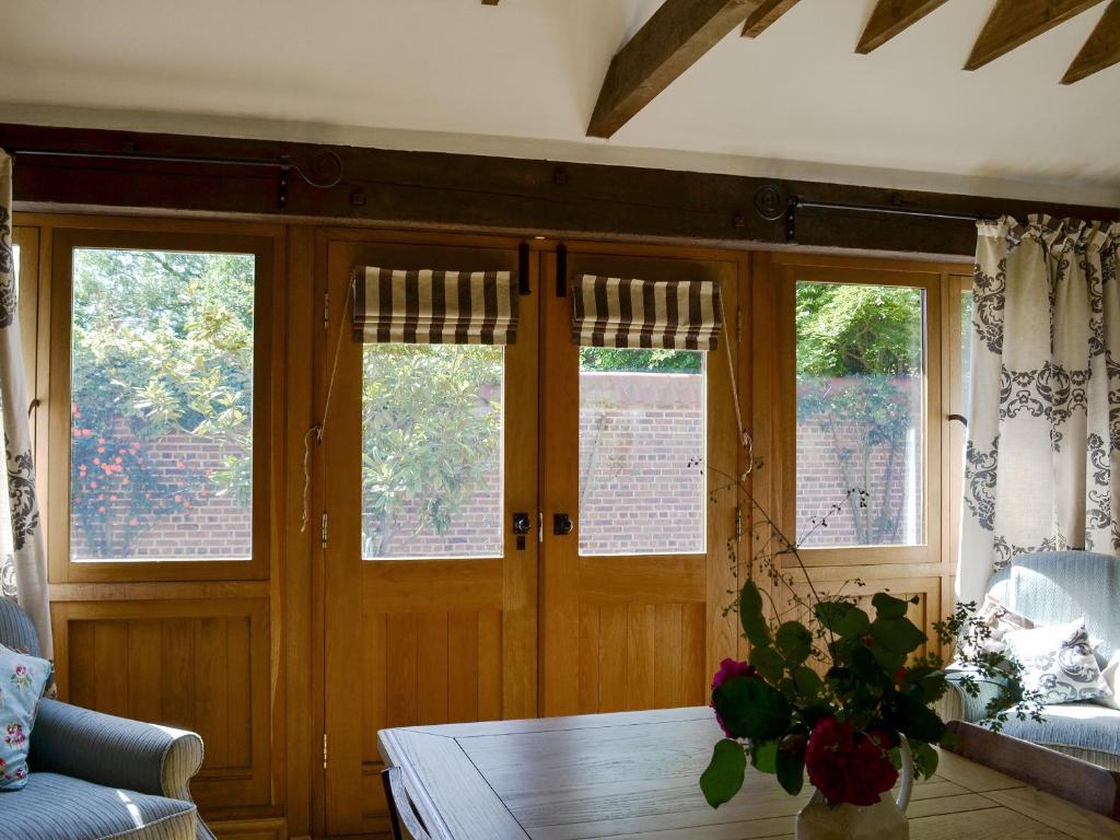a living room with wooden doors and a table at Cornflower Cottage Ukc1897 in Dogdyke