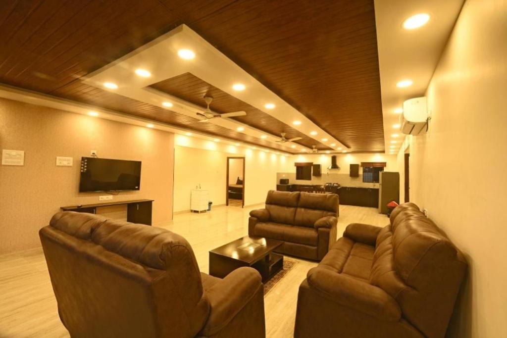 a living room with couches and a flat screen tv at Villa NirvanaPool4BHKPatioLawnACParty Villa in Hyderabad