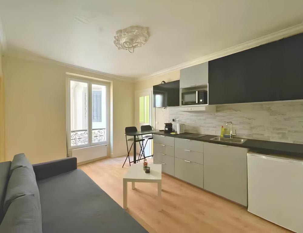 Una sala de estar con un sofá y una cocina. en Cozy appart 15Mn Champs-Élysées, en París