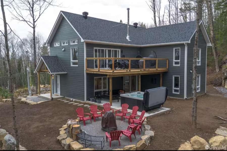 a house with a deck with red chairs and a pool at Spa & Pool table - Chalet D-tente in Saint Come