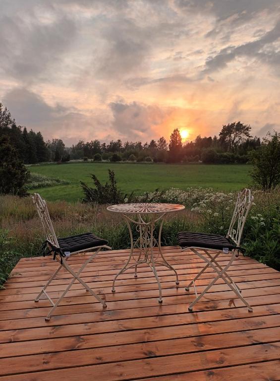 LaitilaGlamping Kotitila Kiveinen的木甲板上的桌椅,享有日落美景