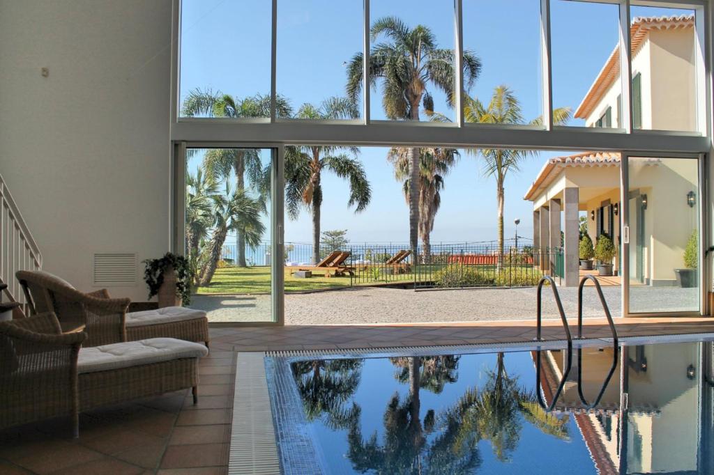 a house with a pool and palm trees at Magnificent Funchal Villa Villa Luzia 5 Bedrooms Sea & City Views in Funchal
