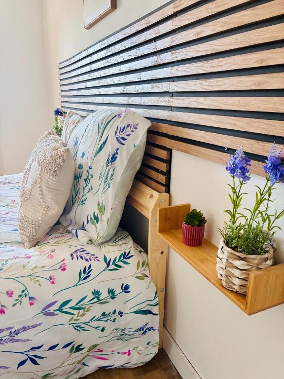 un lit avec une tête de lit en bois et deux plantes en pot dans l'établissement La longère des plages, à Plougonvelin