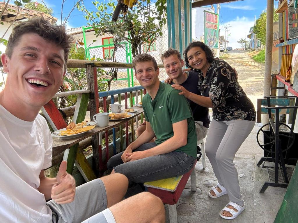 een groep mensen die aan een tafel zitten bij Un Café en el camino Guesthouse in Salento