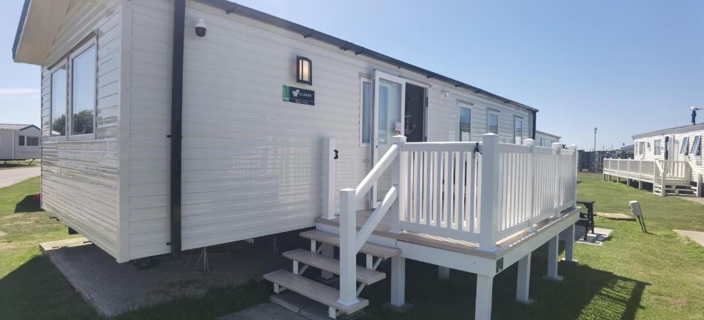 a tiny house with a porch and a staircase at Big Boss Caravan-Camber Sands,Sleep 8, Free Wi-Fi, Netflix, Parking in Camber