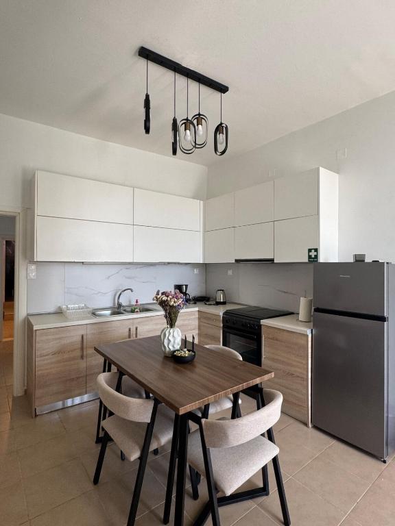 a kitchen with a wooden table and white cabinets at Nikistratos Cozy Apartment in Néa Alikarnassós