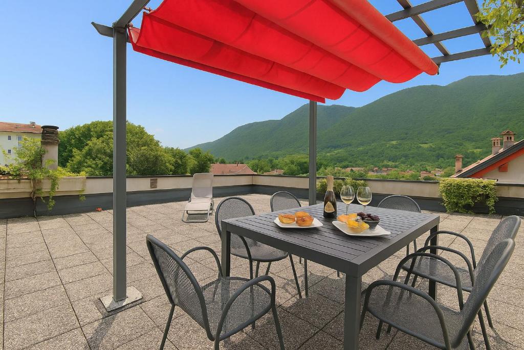 a table with chairs and a red umbrella on a patio at Casa Zaira in Feltre