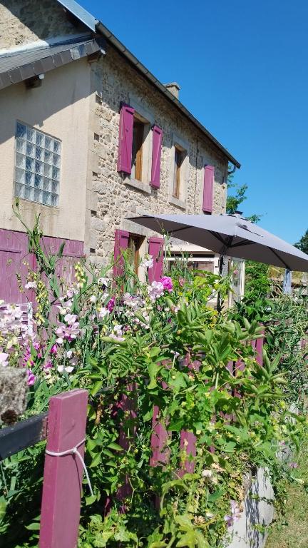 une maison avec des volets roses et des fleurs devant dans l'établissement Maison de vacances belle campagne auvergnate en Combrailles, à Saint-Julien-la-Geneste