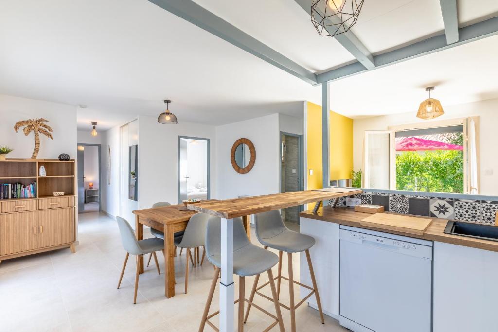 una cucina con tavolo e sgabelli in legno di Gemma - 5 min de la Plage a Ondres