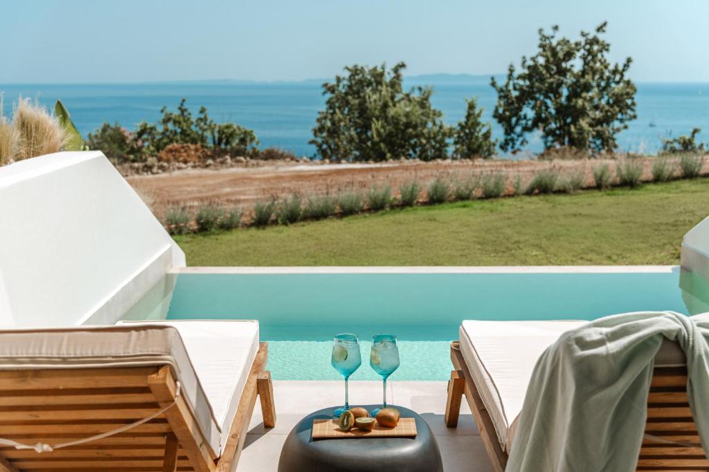 a pair of wine glasses on a table next to a pool at Orizontas Suites in Syvota
