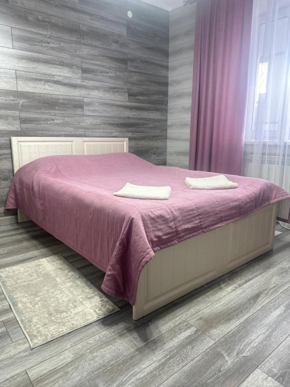 a bedroom with a bed with a purple blanket at Silk Way Hotel in Kokshetau
