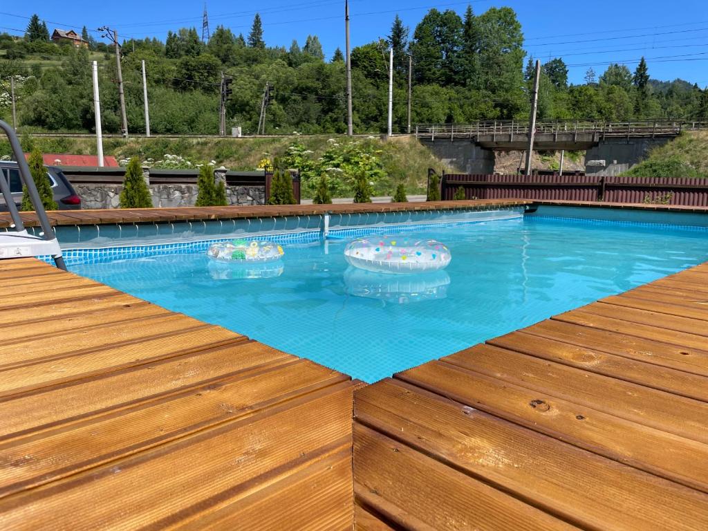 a swimming pool with blue water in a wooden deck at Dimira Котедж з басейном in Slavske