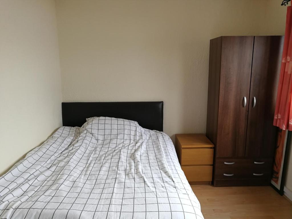 Un dormitorio con una cama y un armario de madera. en Glasgow Room near Glasgow City Centre, en Glasgow