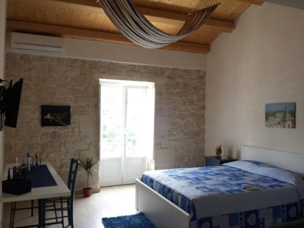 a bedroom with a bed and a desk and a window at Amaca Iblea in Ragusa