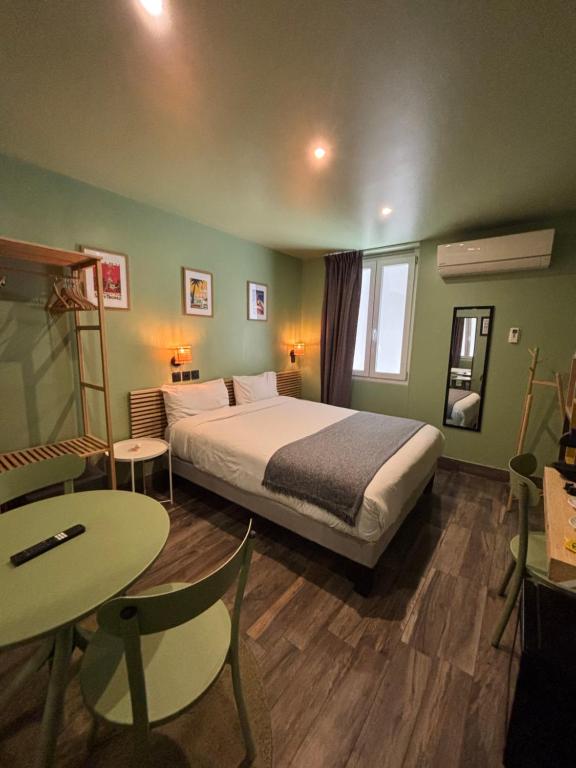 Un dormitorio con una cama y una mesa y sillas. en Hotel de Berne, en Niza