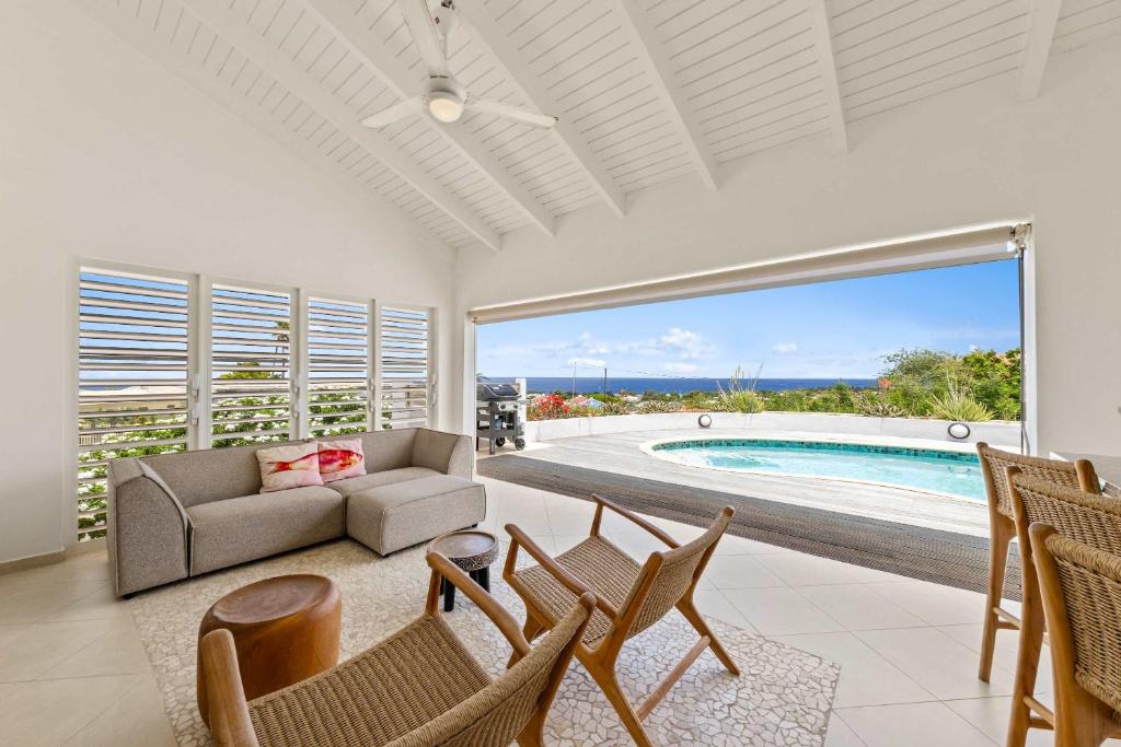 a living room with a couch and chairs and a pool at Dream View Villa in Willemstad