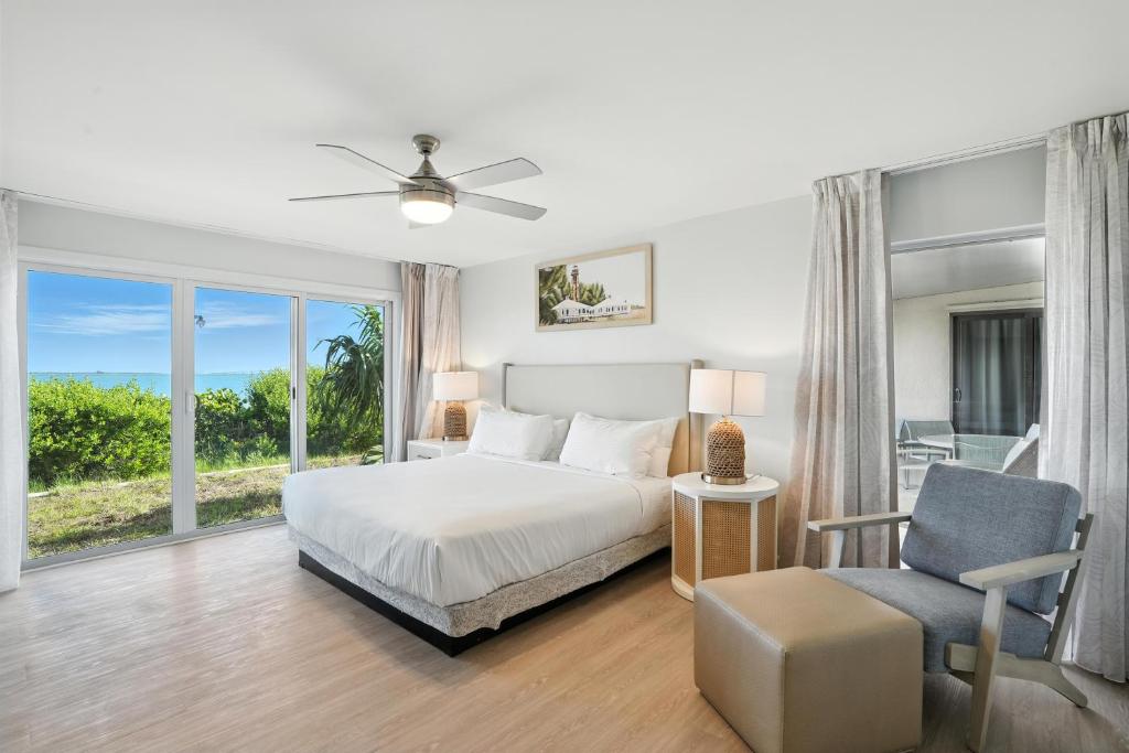 a bedroom with a bed and a chair and a window at Lighthouse Resort & Club in Sanibel