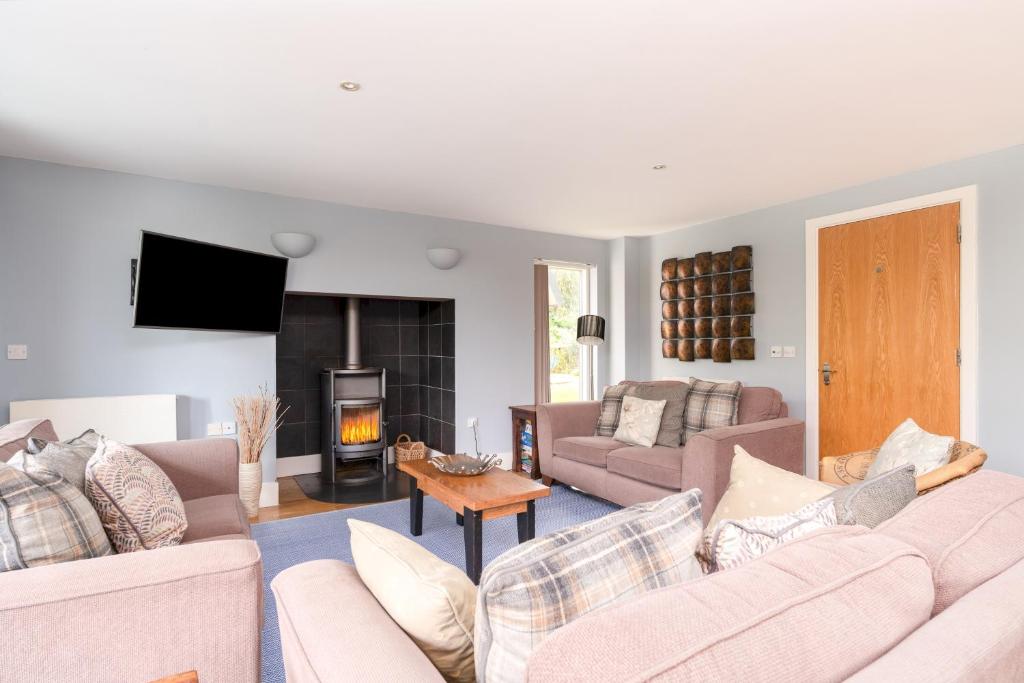 a living room with couches and a fire place at Ducklings CW65 Lower Mill Estate Cotswolds in Somerford Keynes