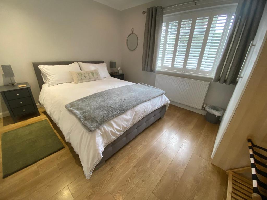 a bedroom with a large bed with a wooden floor at Sun Terrace Lodge Weybridge in Oatlands Park