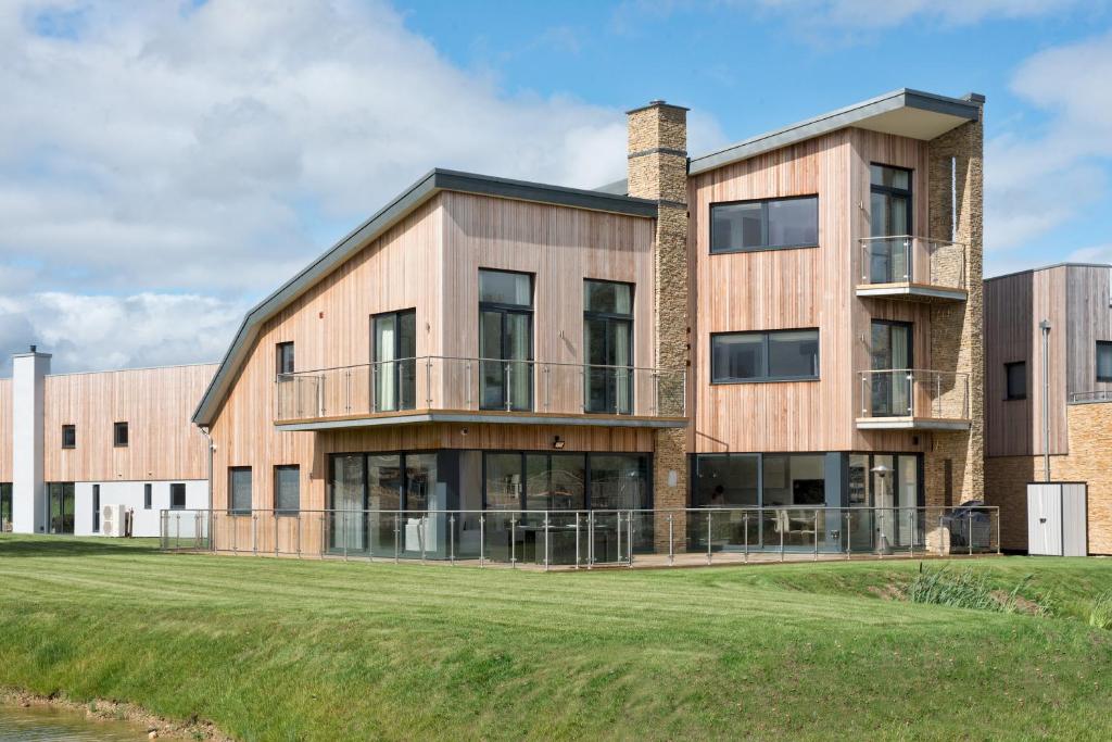 een groot bakstenen gebouw met een grasveld bij The Cotswolds Manor ML26 Lower Mill Estate. in Somerford Keynes