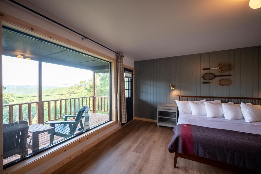 a bedroom with a bed and a large window with a balcony at The Woodsman Lodge in Eureka Springs