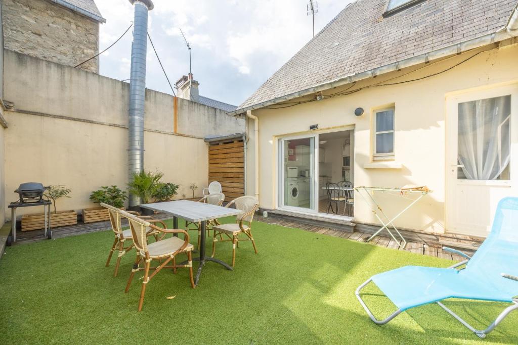 a patio with a table and chairs on the grass at Le Bassin in Port-en-Bessin-Huppain