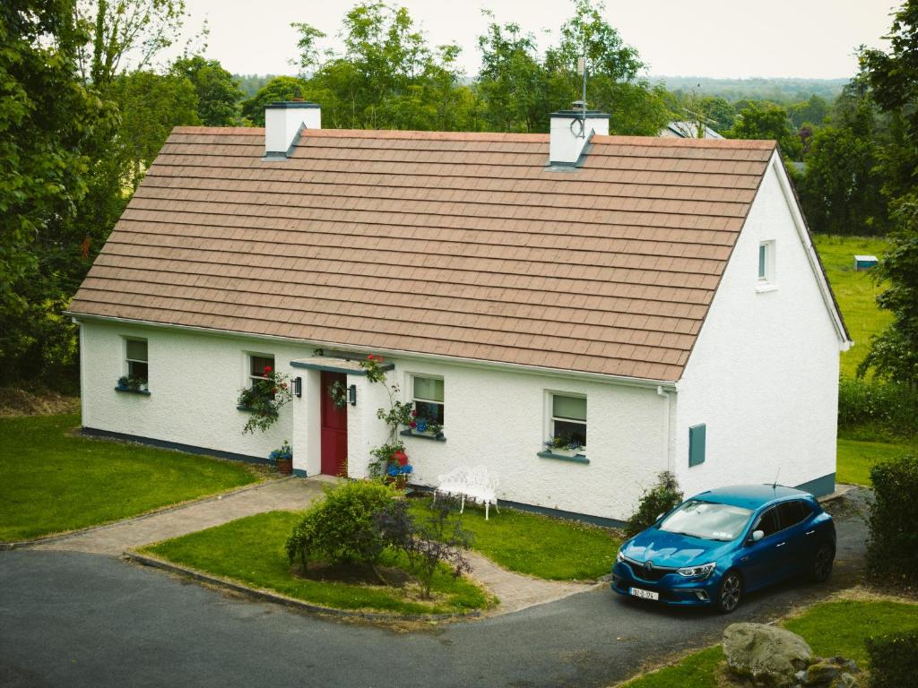 une maison blanche avec une voiture garée devant elle dans l'établissement Longford Holiday Red Rose Self Catering Cottage, à Longford