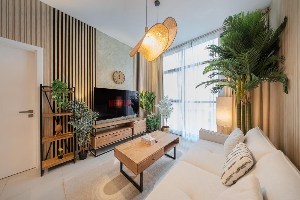 a living room with a white couch and a tv at Forest Honeymoon Suite With Pool View by BlueCloud holidays in Sharjah