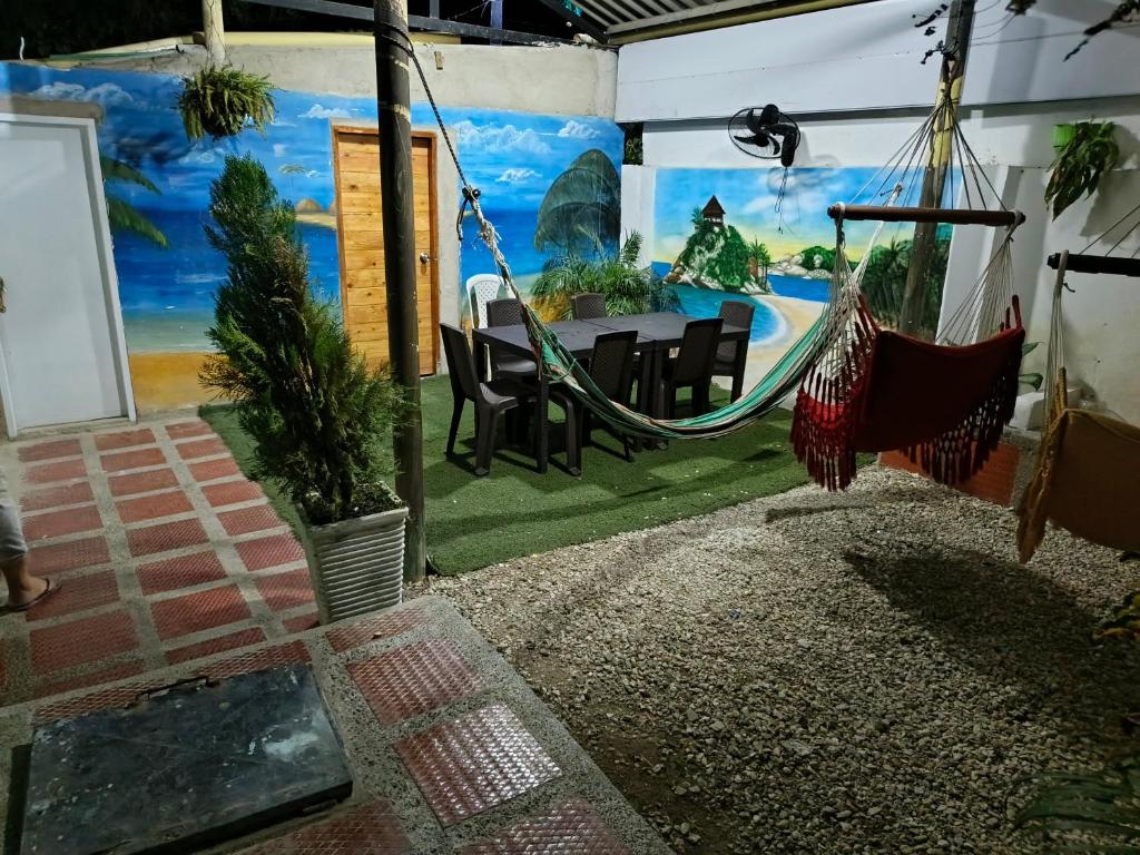 Habitación con hamaca, mesa y sillas. en Casa alojamiento las acacias, en Santa Marta