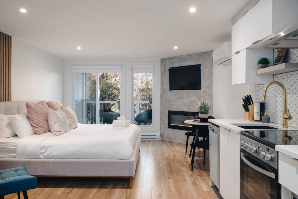 a white living room with a couch and a kitchen at LAÖ Loft Tremblant #106 - KING size Bed in Mont-Tremblant