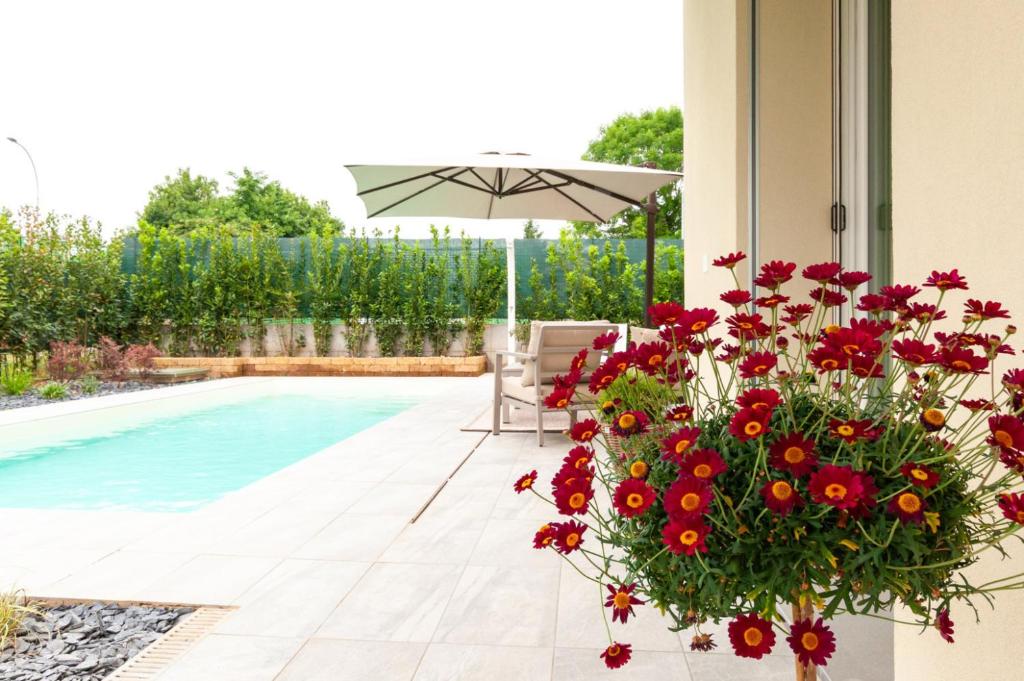 une terrasse avec des fleurs rouges et une piscine dans l'établissement Villa Melodica, à Carzago della Riviera