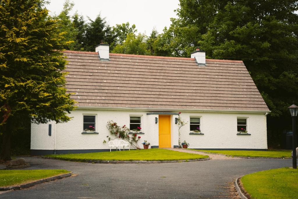 uma casa branca com uma porta e janelas amarelas em Longford Holiday Yellow Star Self-Catering Cottage em Esker South