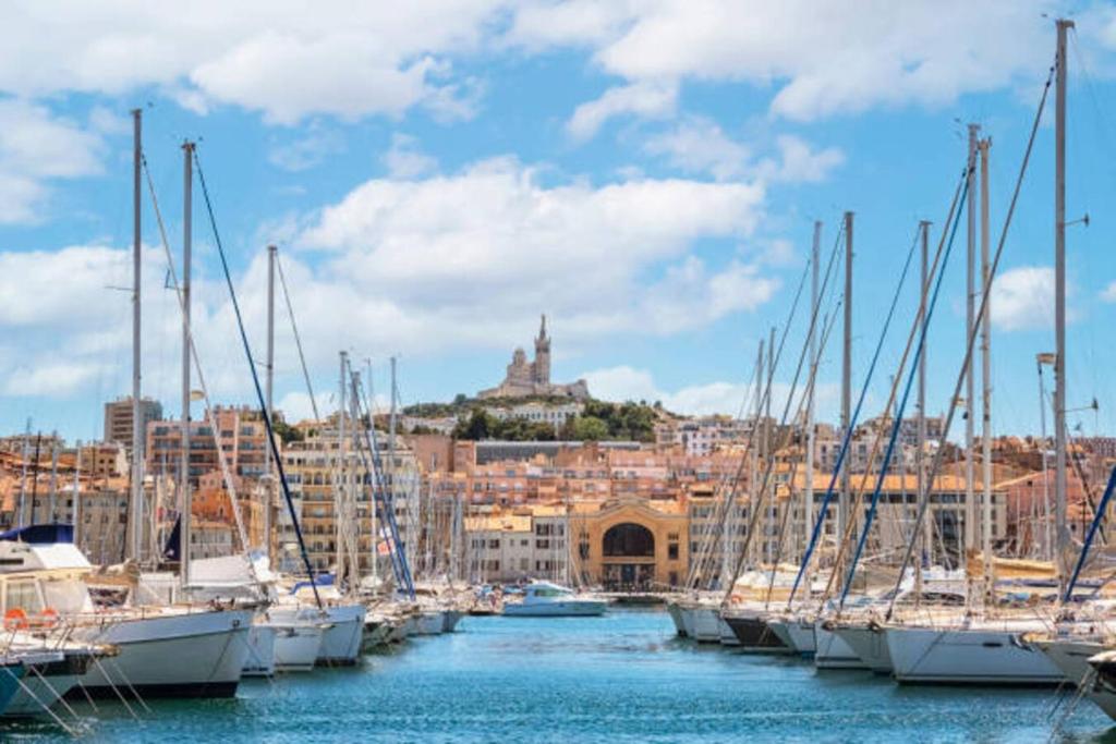 Une bande de bateaux amarrés dans un port avec une ville dans l'établissement Yacht idéalement situé au coeur du Vieux-Port, à Marseille