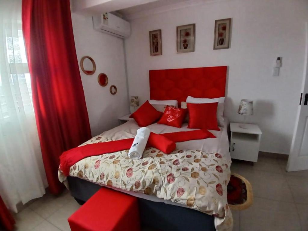 a bedroom with a large bed with red pillows at Orca Estate Guesthouse Self-catering Accommodation in Durban