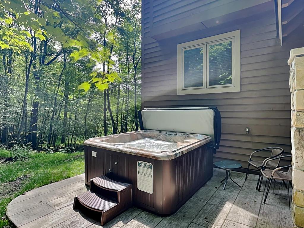 a hot tub sitting on a deck next to a house at Play-A-Way Chalet in McHenry