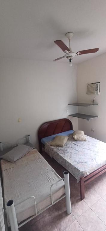 two beds in a room with a ceiling fan at Suite027 3p in Guarapari
