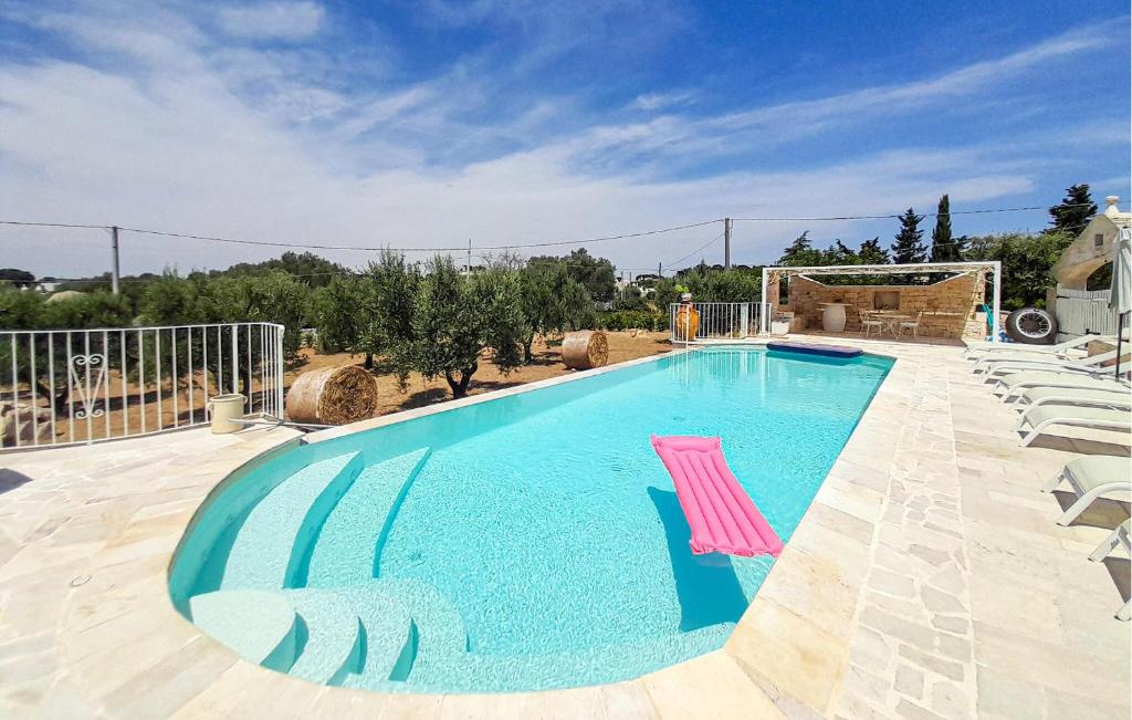 Una gran piscina con una silla rosa al lado. en Amazing Home In Cisternino, en Cisternino