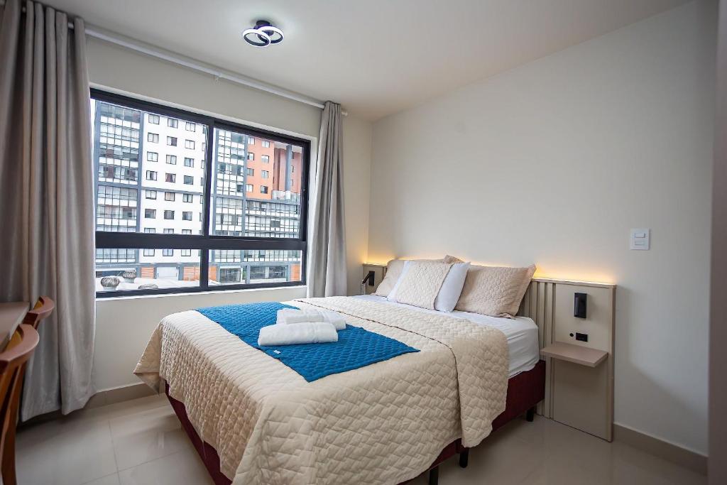 a bedroom with a bed with a large window at MUV proximo ao shopping in Curitiba