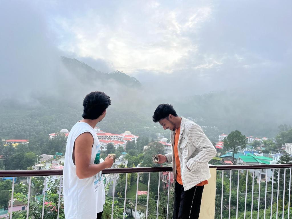 BhowāliにあるSoul Homestayのバルコニーに立って携帯電話を見ている2人の男性