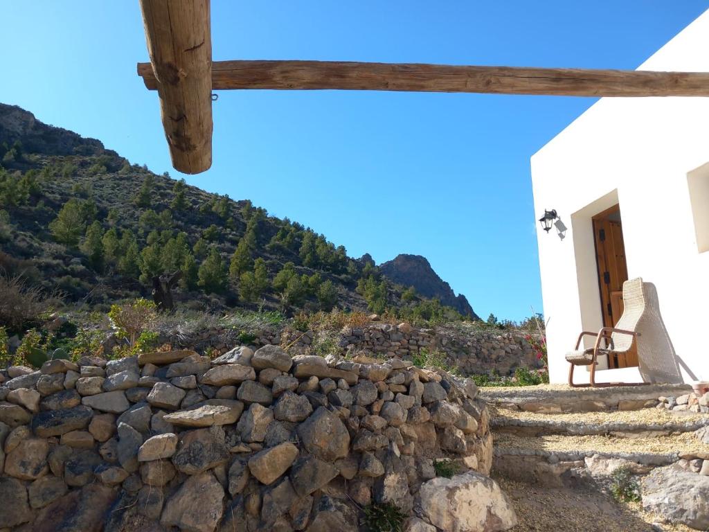 a stone wall in front of a building with a mountain at Kortijo Martzala in Lucainena de las Torres