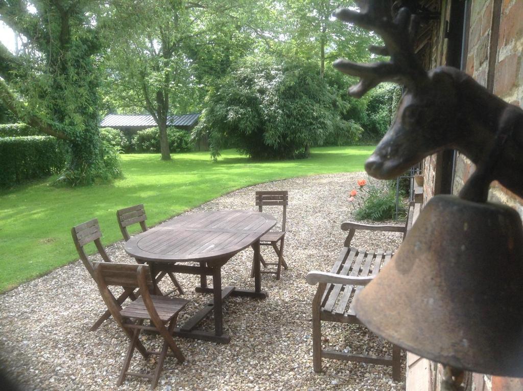 a table and chairs and a statue of a deer at Charmante Petite Maison dans le Jardin in Letteguives