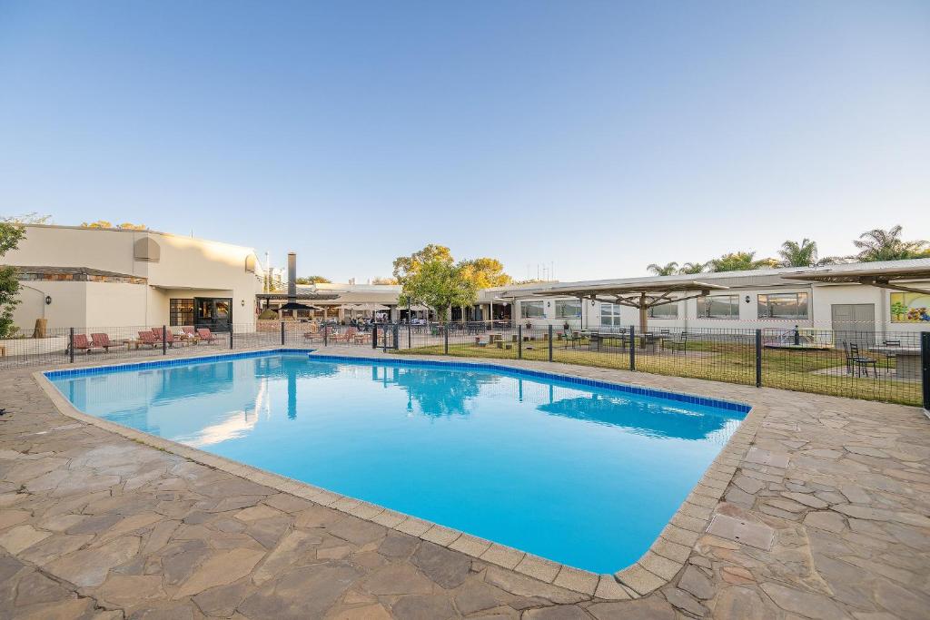 a large swimming pool with blue water at Safari Lodge in Windhoek