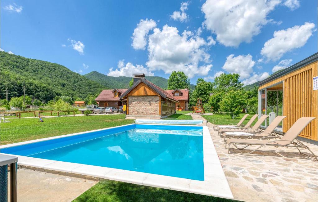 a swimming pool in a backyard with chairs and a house at Nice Home In Gospic With Sauna in Gospić