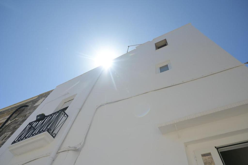 a white building with the sun shining on it at A L Tourist House - La Corte Bianca - La Torre Blu in Carovigno