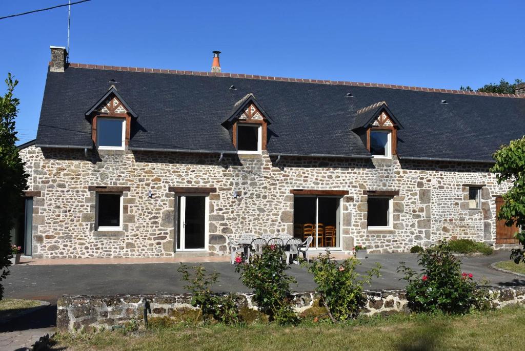 a stone house with a black roof at Gîte La Mancellière - Maison familiale 12-15 pers, grand jardin, jeux & pétanque - Pleine nature in Cigné