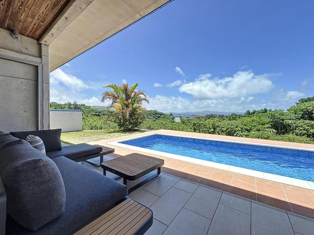 a living room with a couch and a swimming pool at ulu Okinawa Resort in Motobu